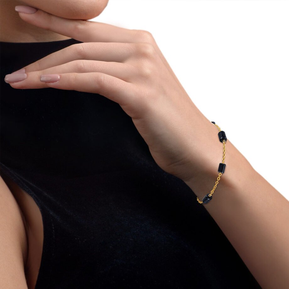 Mujer vestida de negro luciendo pulsera piedras oro angélica formada por ónix